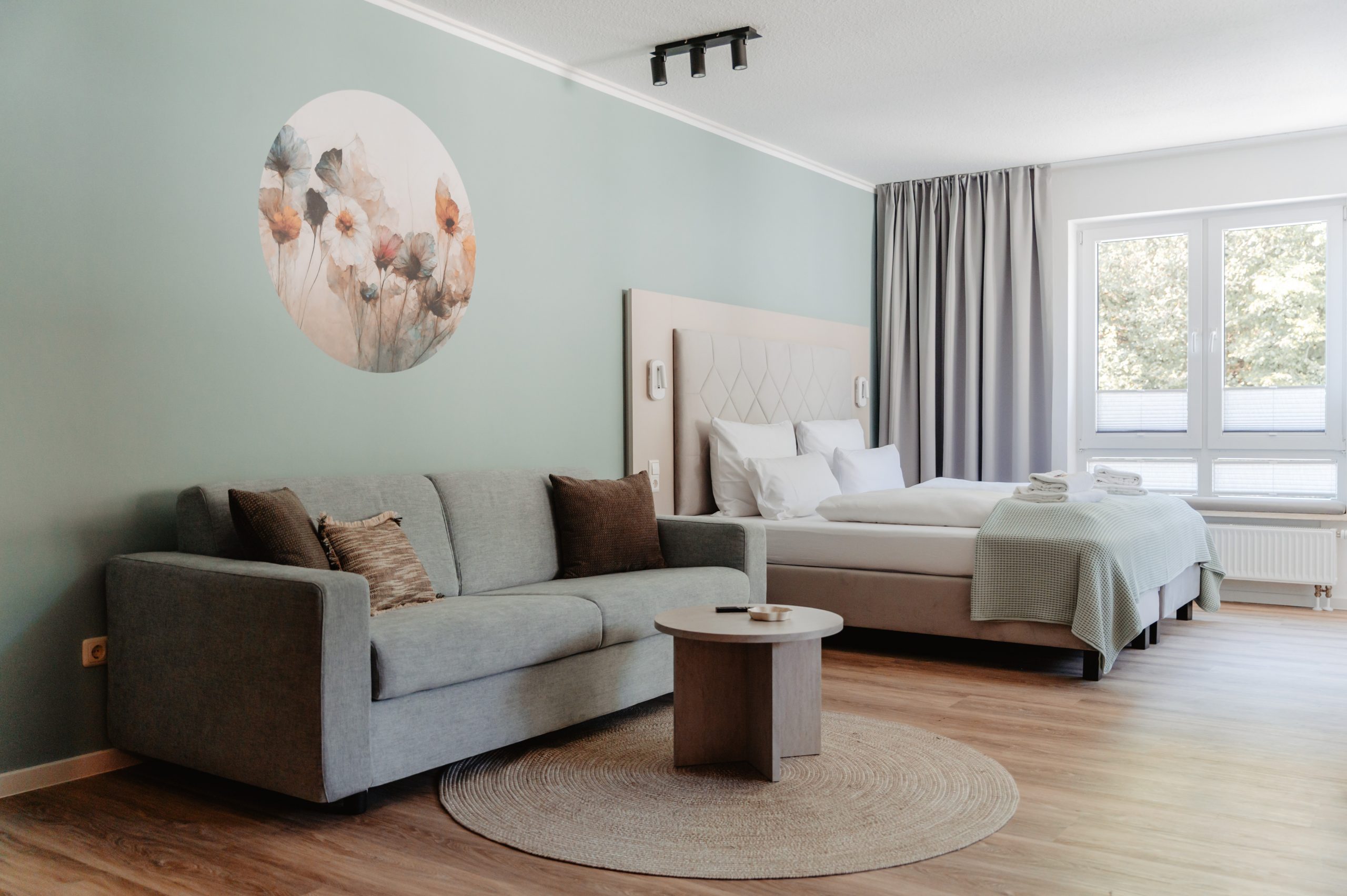 Junior Apartment im HarzHold in Lerbach – Schlafzimmer mit Sofa, Couchtisch und Doppelbett